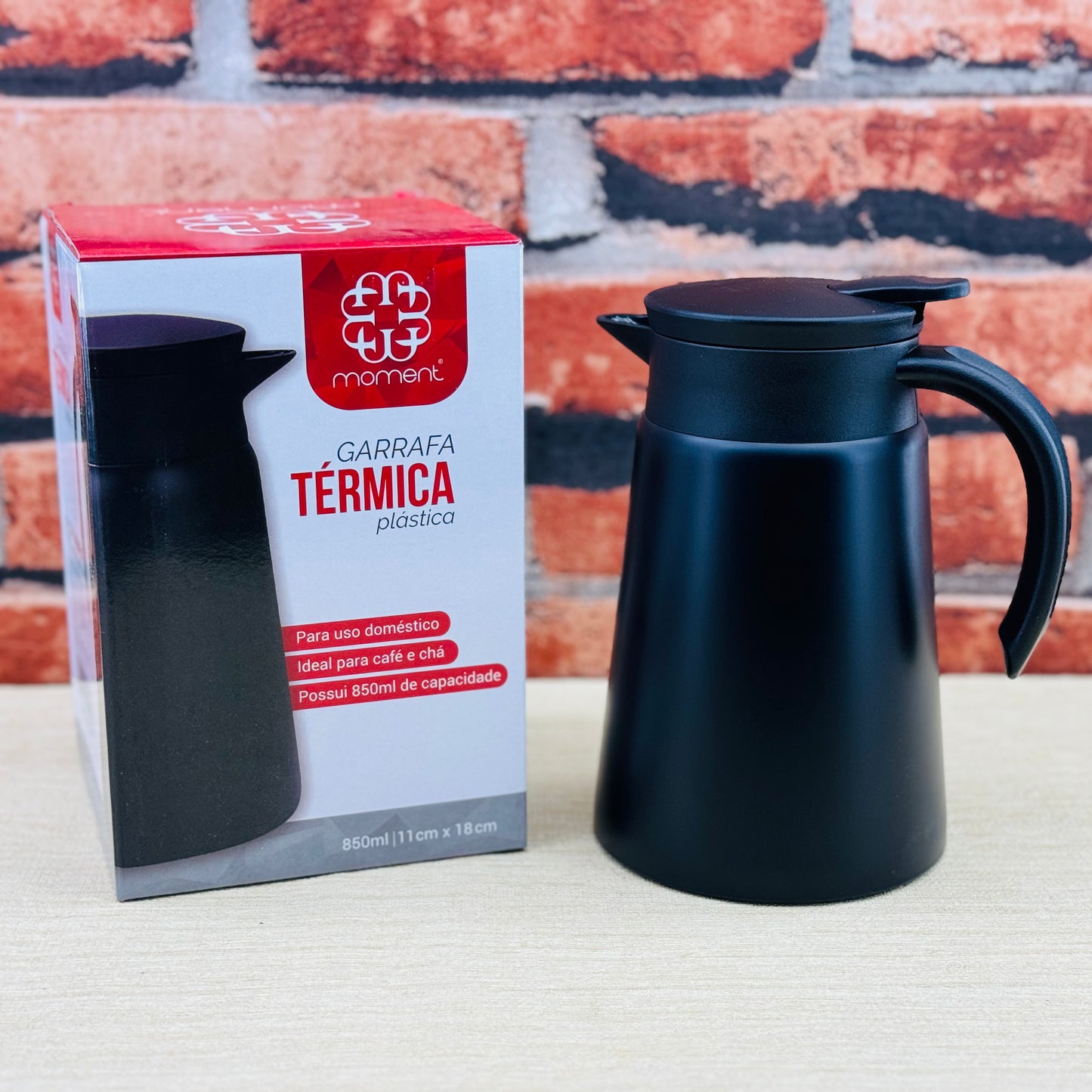 A black stainless steel coffee pot teapot with a cool handle and a non-slip silicone bottom, placed next to its packaging box which has 'GARRAFA TERMICA' written on it.