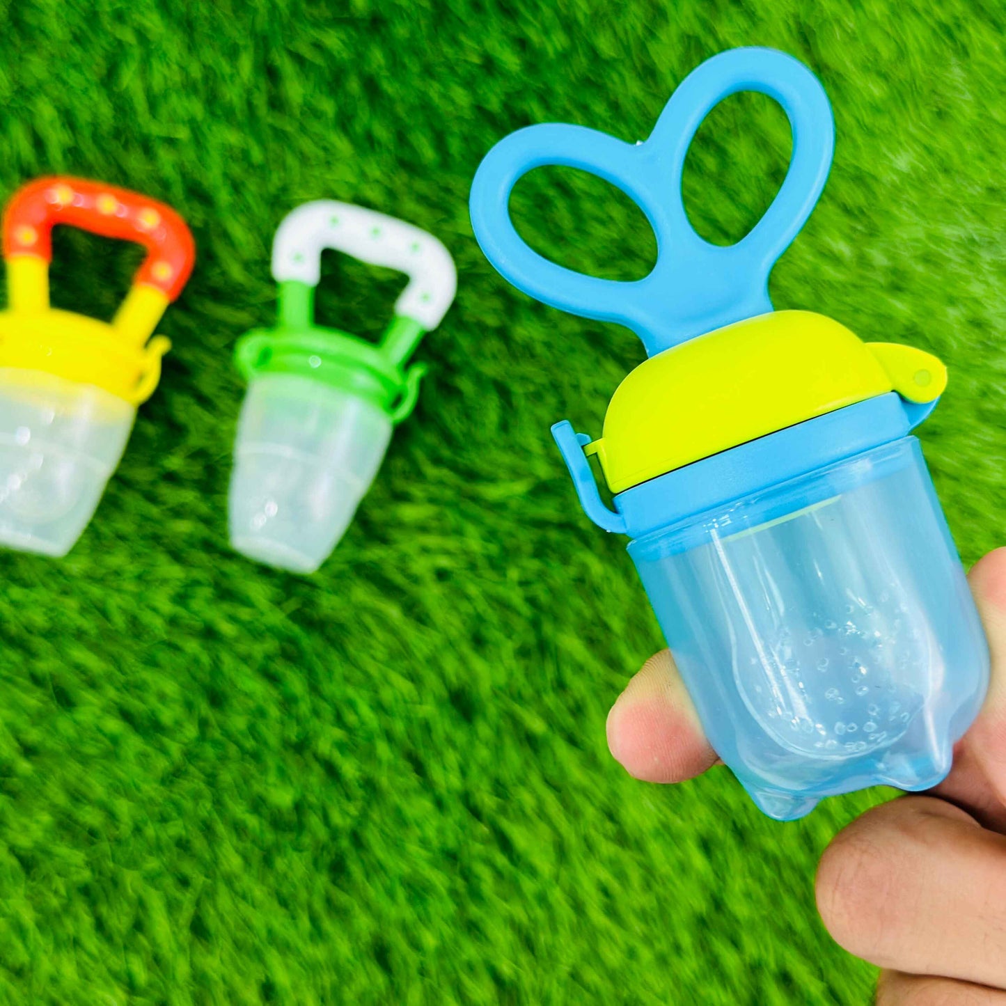 Colorful baby pacifiers on a green textured background