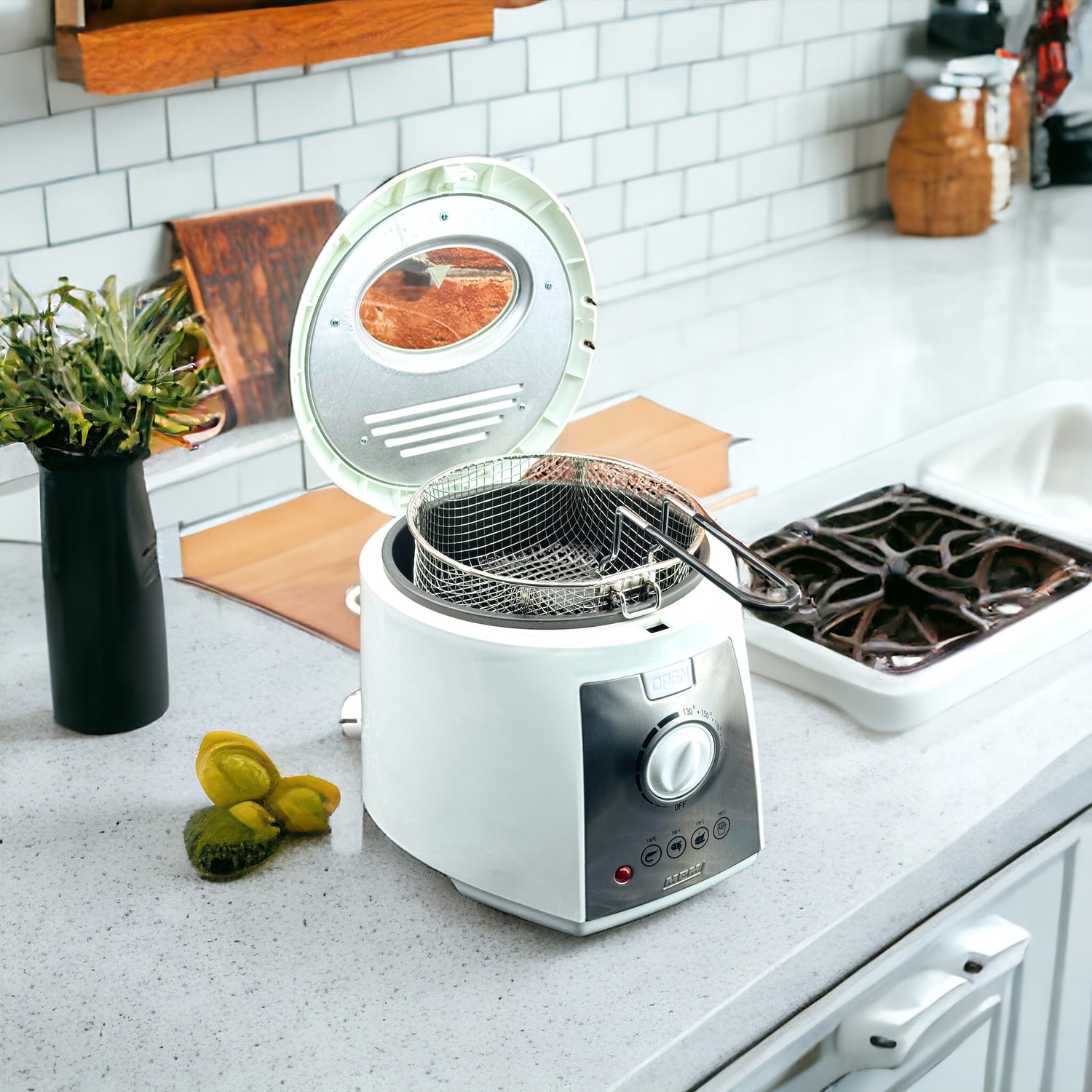 Compact electric deep fryer in white, with a non-stick bowl, displayed on a kitchen countertop with food items around it.