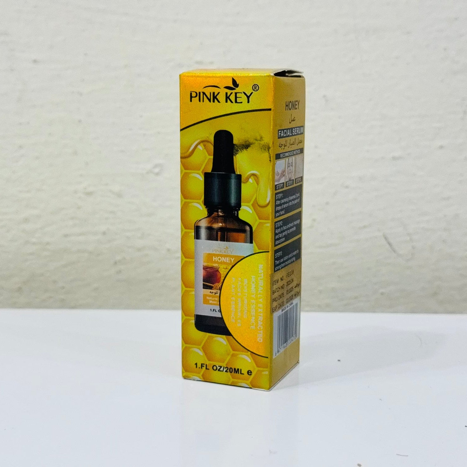 Pink Key bottle and box on a white surface with a light gray textured background