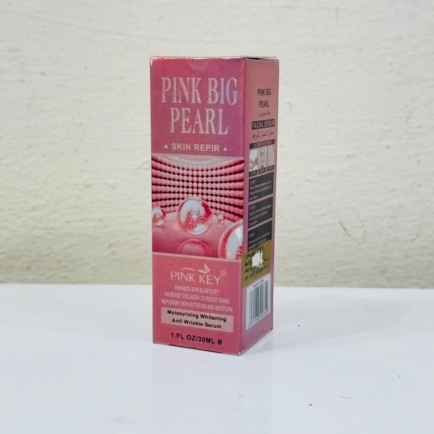 Pink Big Pearl skin repair product packaging on a white surface with a light gray textured background