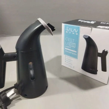 Black handheld steamer next to its packaging box on a gray surface