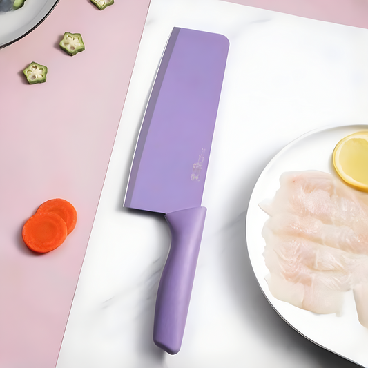 Purple knife on a cutting board with vegetables and fish plate in the background