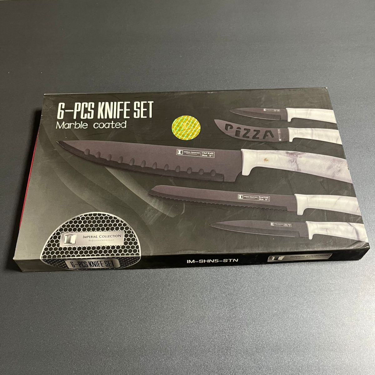 Box of a 6-piece knife set with marble coating on a gray surface