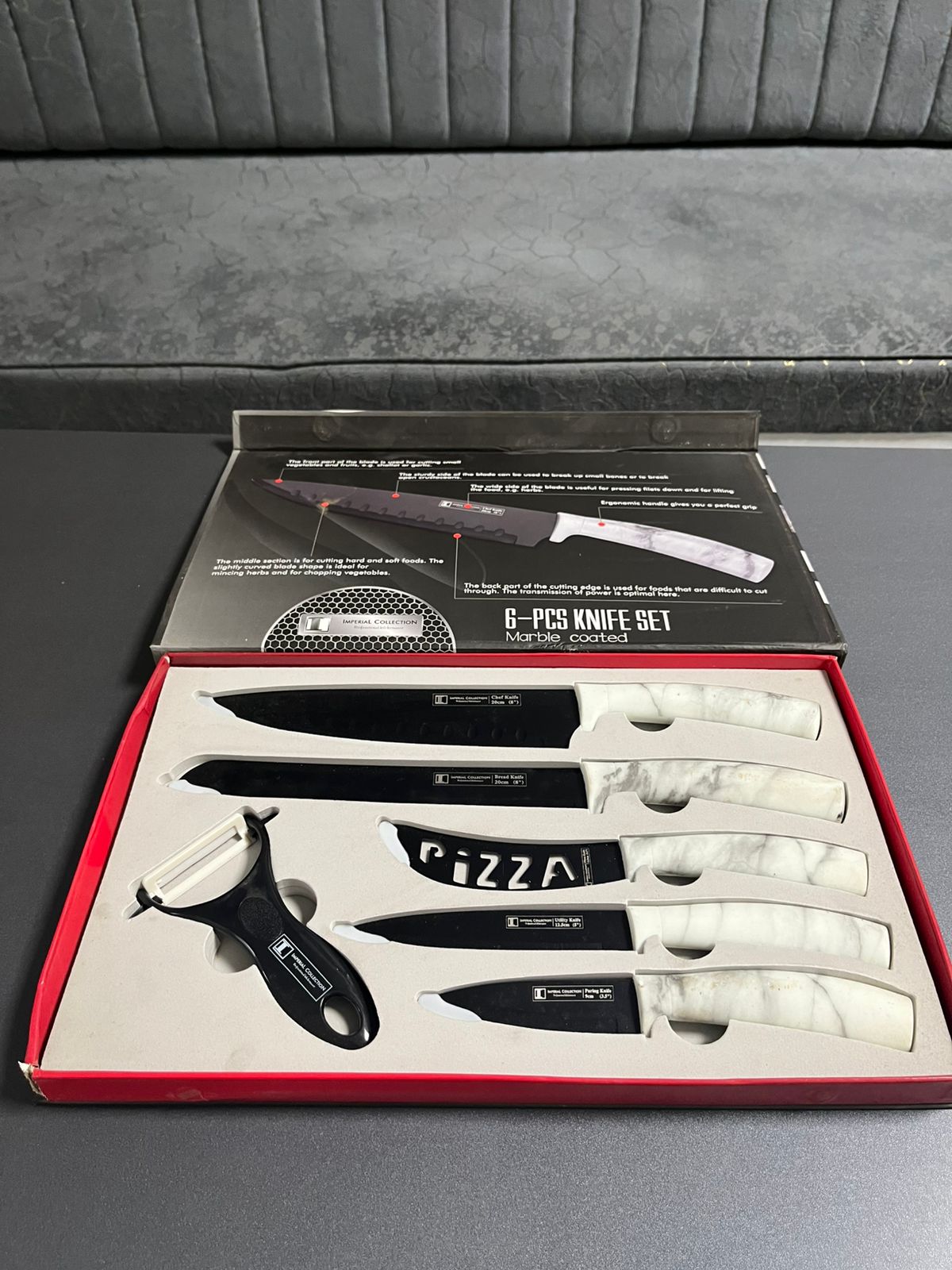 Set of knives and pizza cutter in a box on a gray surface