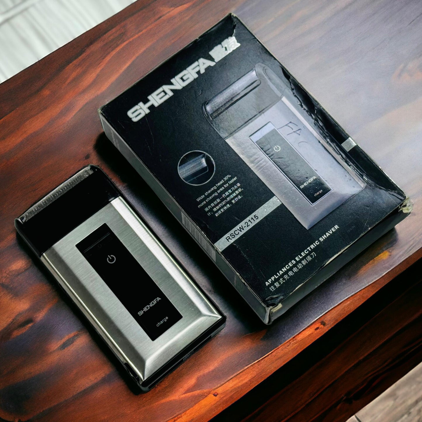 A professional hair shaver by SHENGFA, displayed next to its packaging box on a wooden surface.