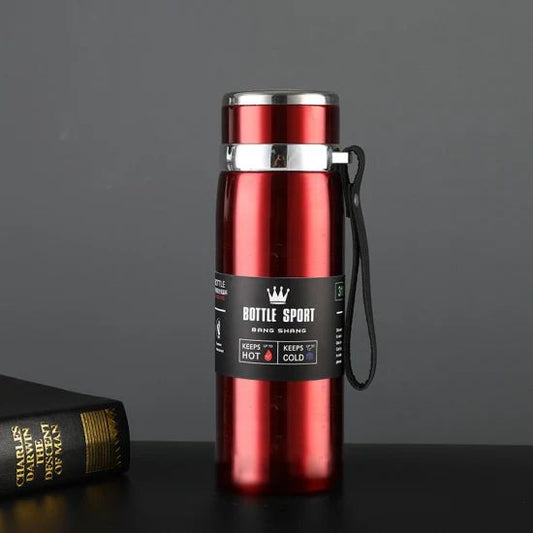 Red thermos bottle with a black label on a dark surface and gray background