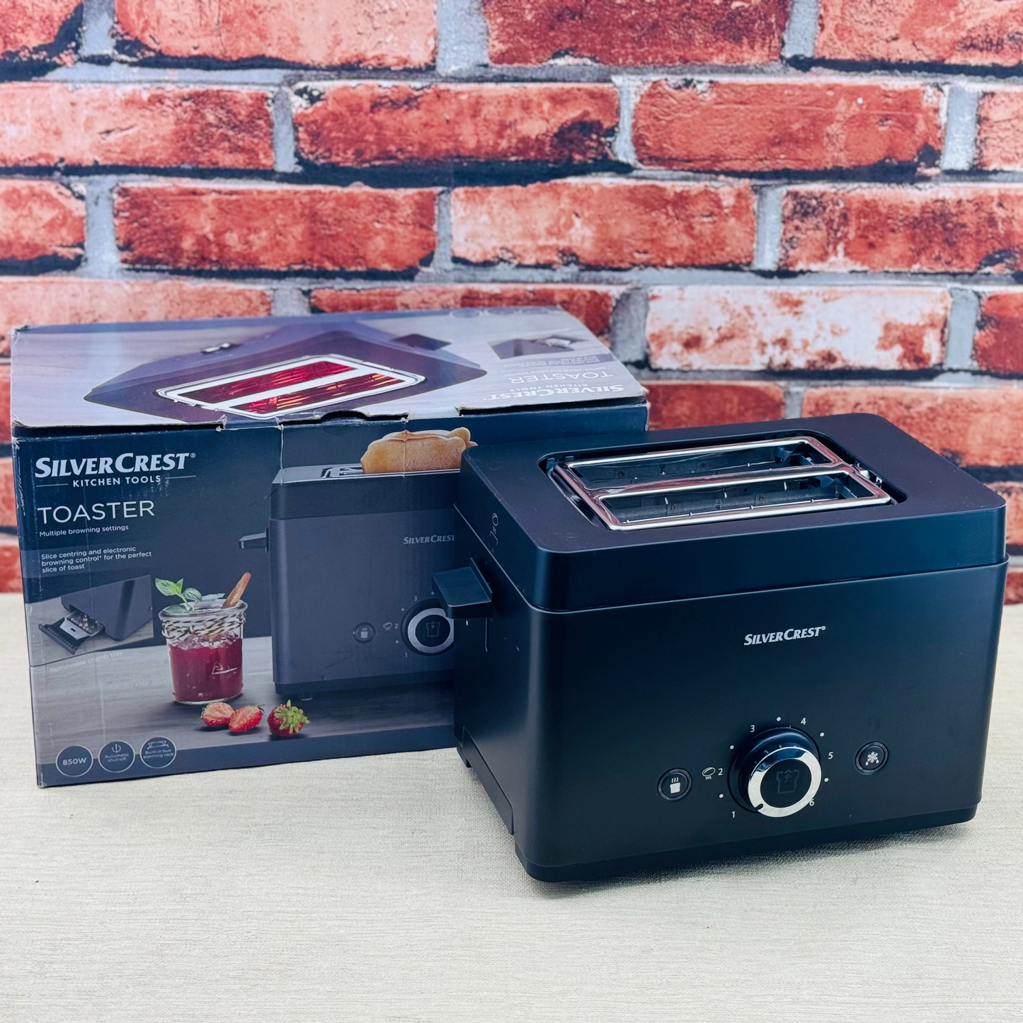 Silver Crest 2-slice bread toaster in black color, displayed alongside its packaging.