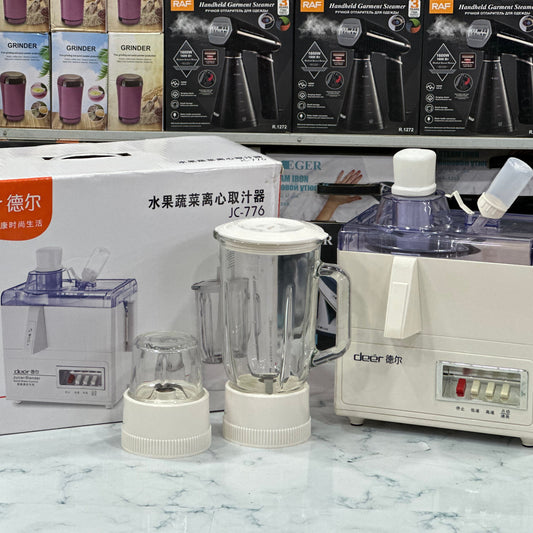 A white Deer brand juicer blender set, including a juicer, blender jug, and grinder, displayed on a counter with its packaging box in the background.