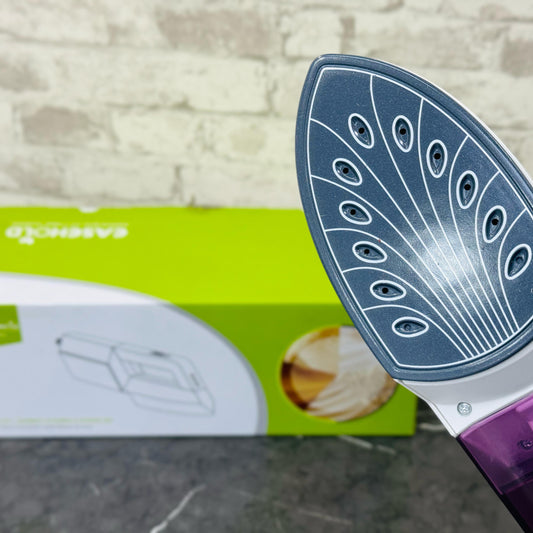 A purple garment steamer with a peacock feather design on the soleplate, displayed alongside its packaging box.