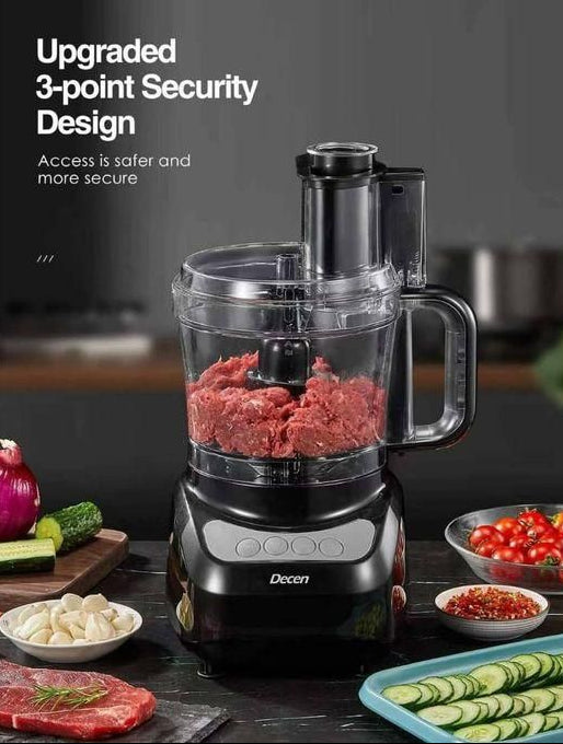 Black food processor with ground meat on a kitchen counter, surrounded by vegetables and ingredients.