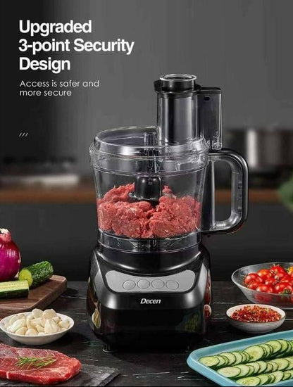 Black food processor with ground meat on a kitchen counter, surrounded by vegetables and ingredients.