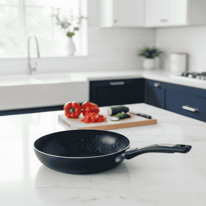 Black frying pan on a kitchen counter with vegetables and a cuttaing board.