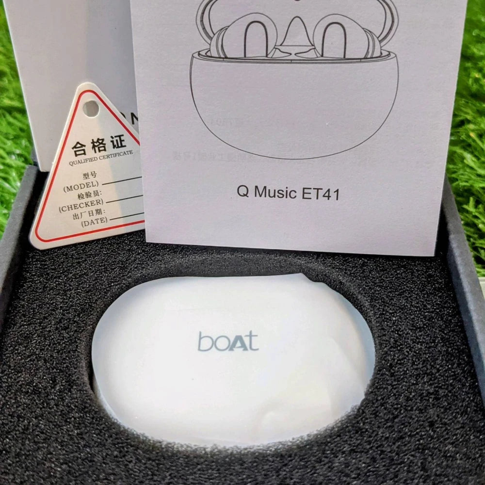 Boat Q Music ET41 wireless earbuds in a box with a certificate of qualification on a grass background