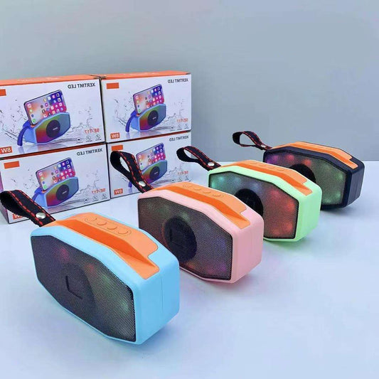 Colorful portable speakers with boxes in the background on a light gray surface