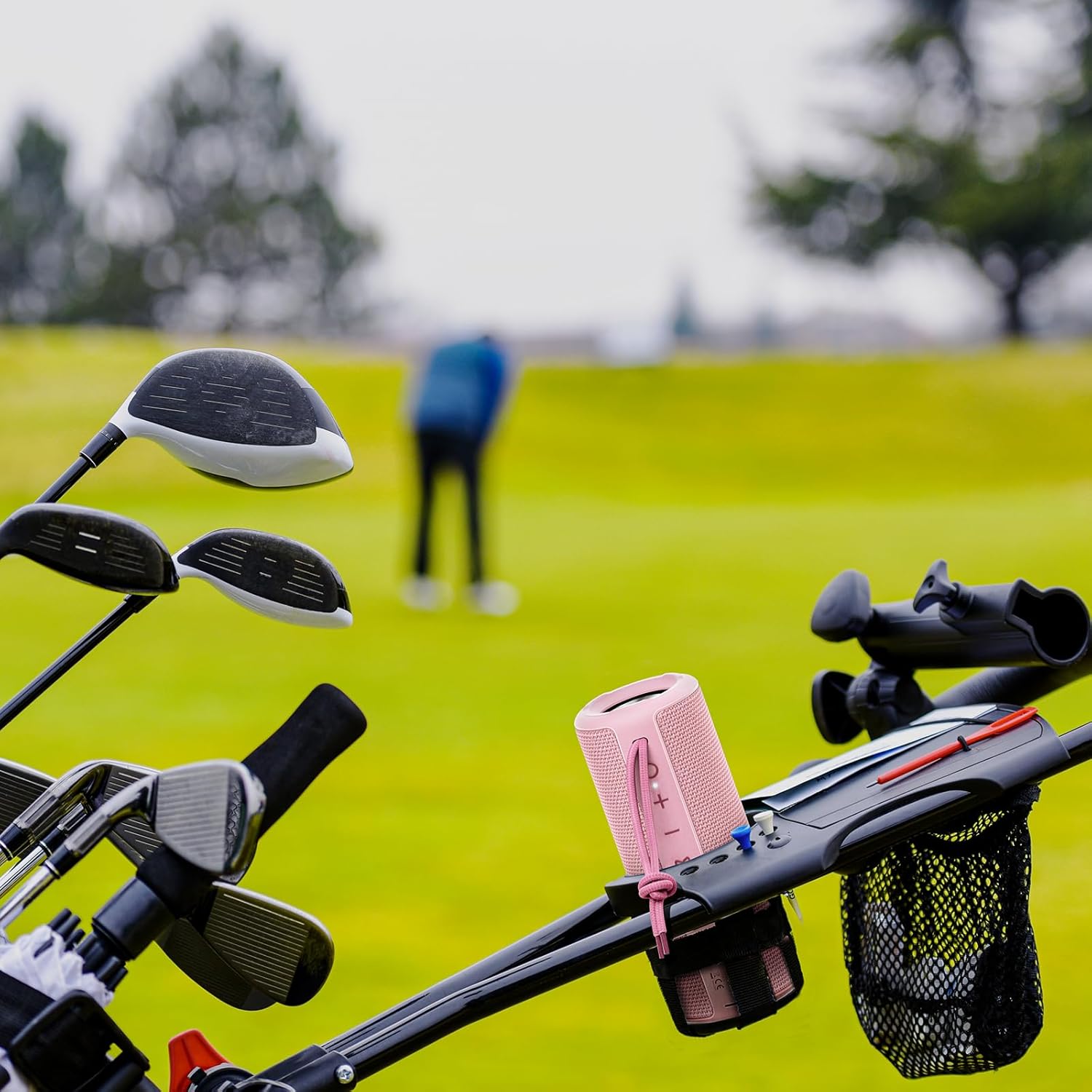 Golf clubs and a pink bag on a golf cart with a blurred golf course background
