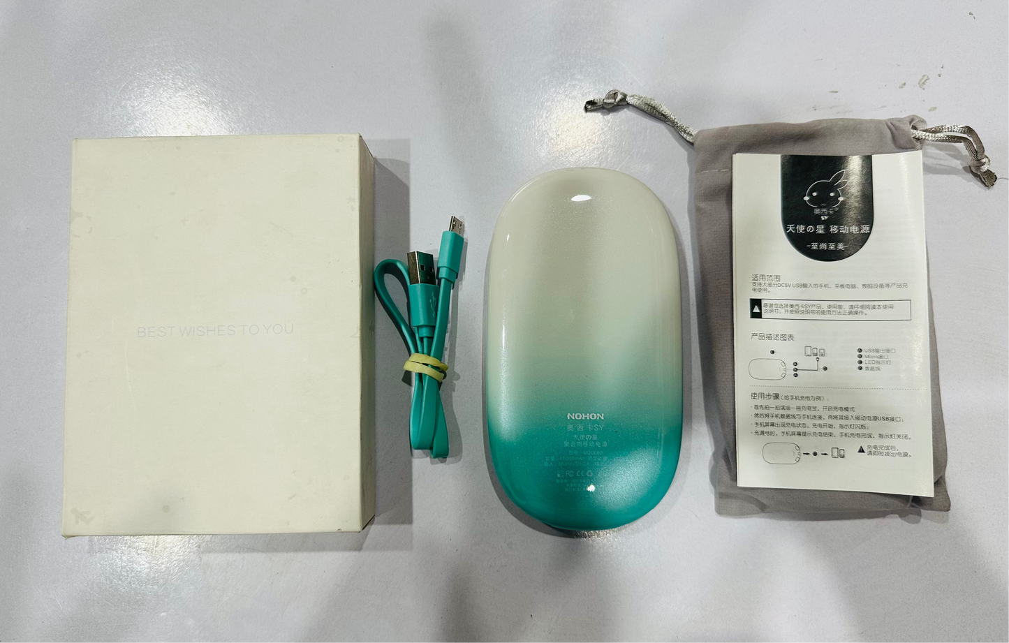 Teal and beige electronic device with USB cable and manual on a white surface
