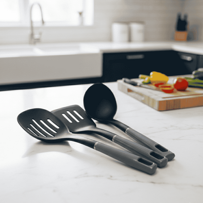 Set of black kitchen utensils on a white countertop with a blurred kitchen background