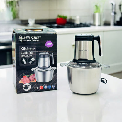 Silver Crest meat grinder with a 3.3L stainless steel bowl, displayed next to its packaging box in a kitchen setting.