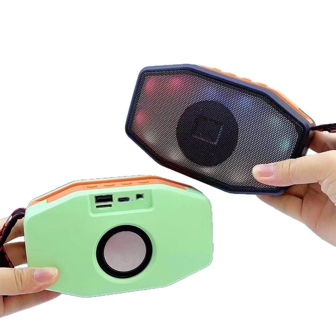 Two portable speakers, one green and one black with orange accents, held by a hand on a white background.