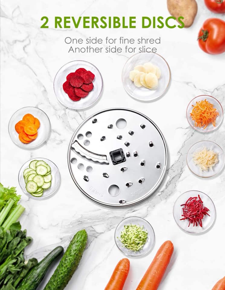 Vegetable shaver with reversible discs on a marble surface with vegetables around