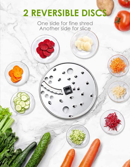 Vegetable shaver with reversible discs on a marble surface with vegetables around