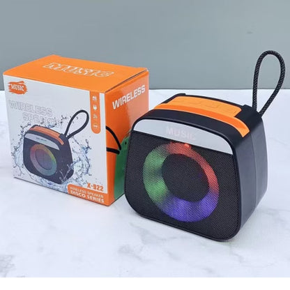 Wireless speaker with colorful LED lights next to its packaging on a white surface.