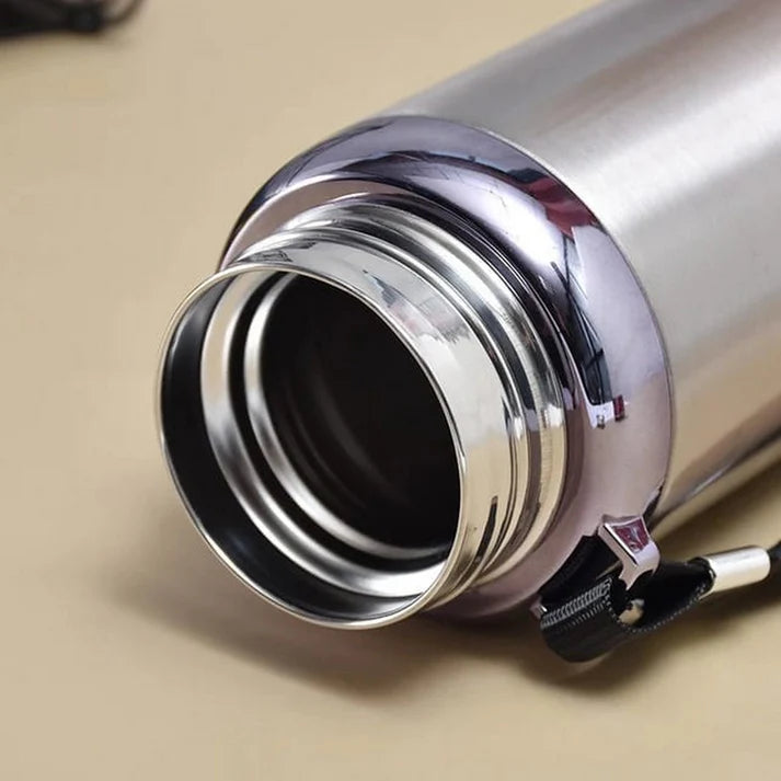 Close-up of a silver thermos with a black interior on a beige surface
