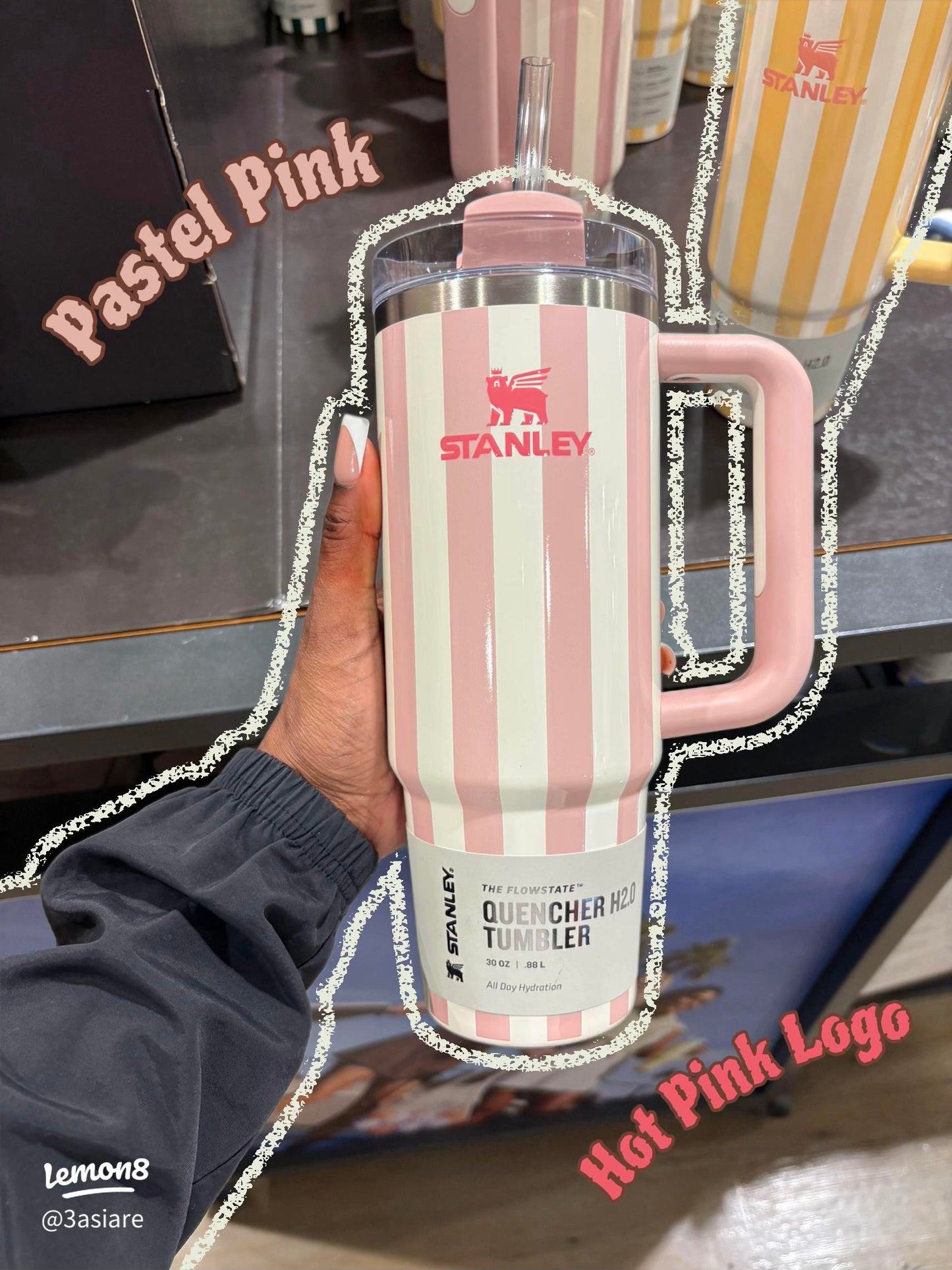 Pink and white striped Stanley tumbler held by a person with a blurred background