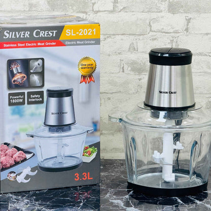 Silver Crest electric chopper in a 3.3 liter glass bowl, with packaging box and a manual, on a kitchen counter.