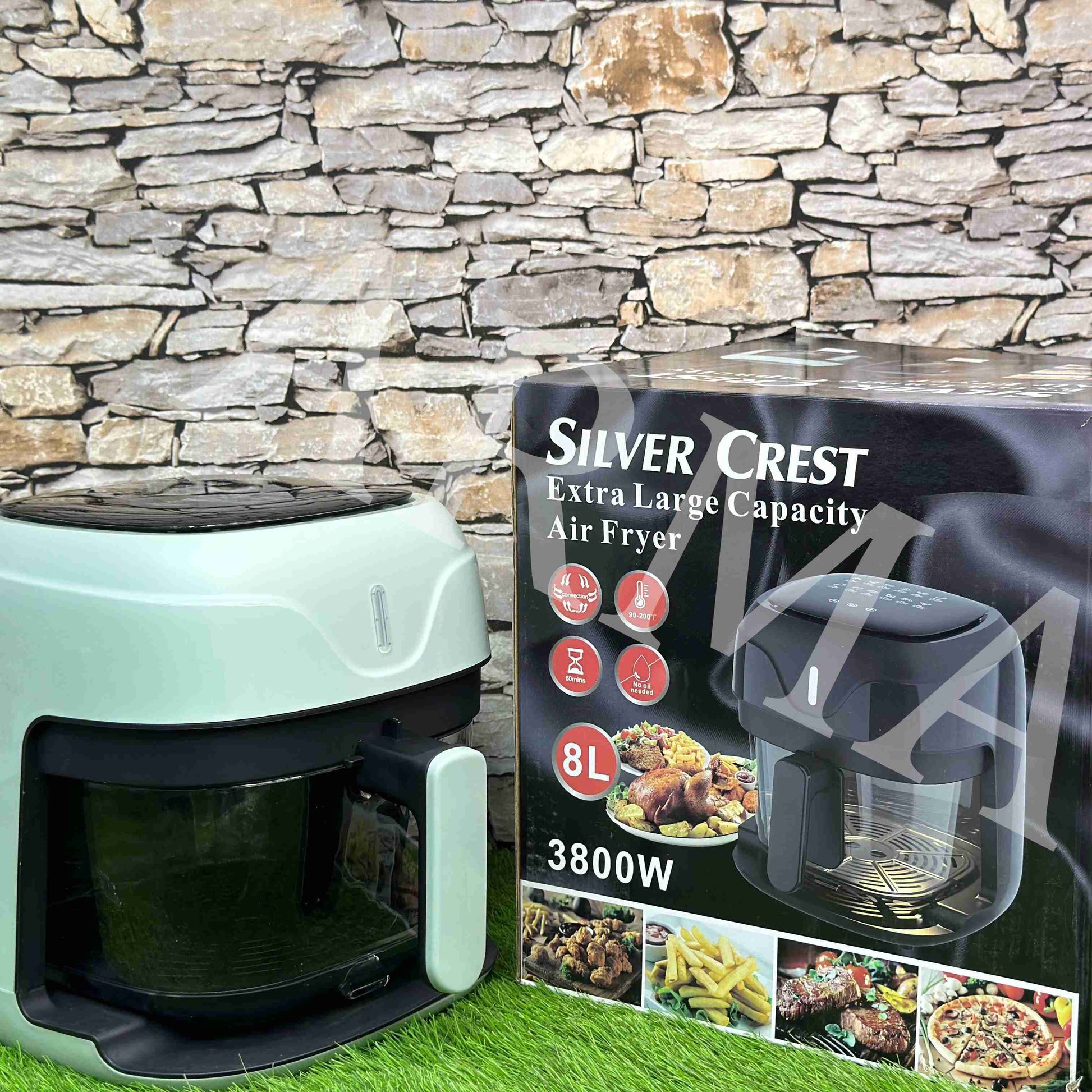 Green air fryer with Silver Crest packaging against a stone wall background