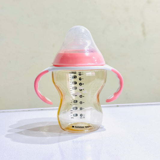 Baby bottle with pink handles on a white surface