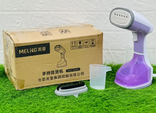 A handheld garment steamer with a purple base and a black handle, accompanied by a brown cardboard box with 'MEILING' brand markings and a small plastic cup.