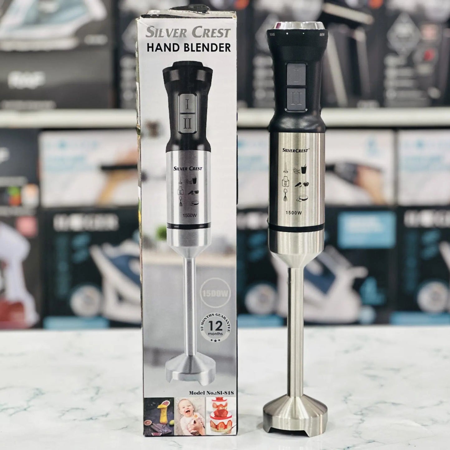 Silver Crest Hand Blender packaging box with the product displayed in front of the box. The blender has a stainless steel look with a black plastic handle.